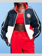 Person wearing a navy, red, and white tracksuit with a blue background