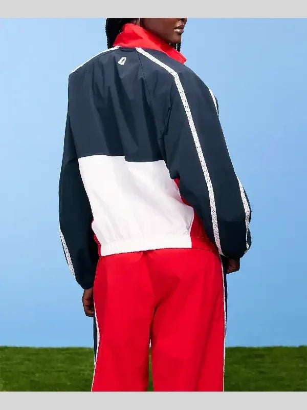 Person wearing a navy, white, and red tracksuit against a blue sky.