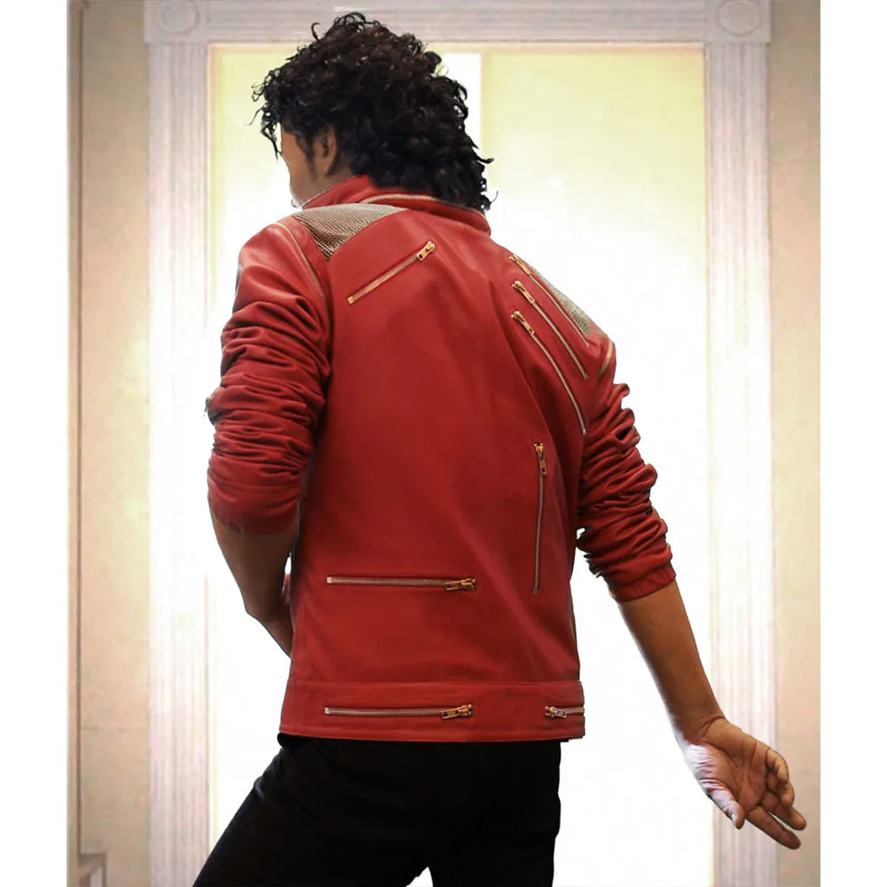 Person wearing a red leather jacket with gold zippers, standing in front of a white curtain.